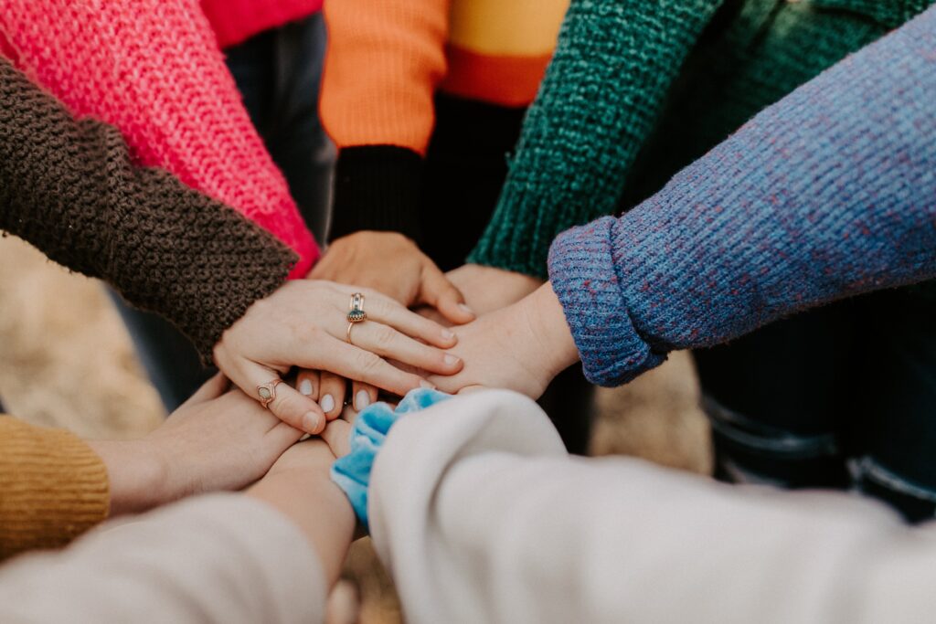 hannah-busing-Zyx1bK9mqmA-unsplash people putting their hands together in a circle