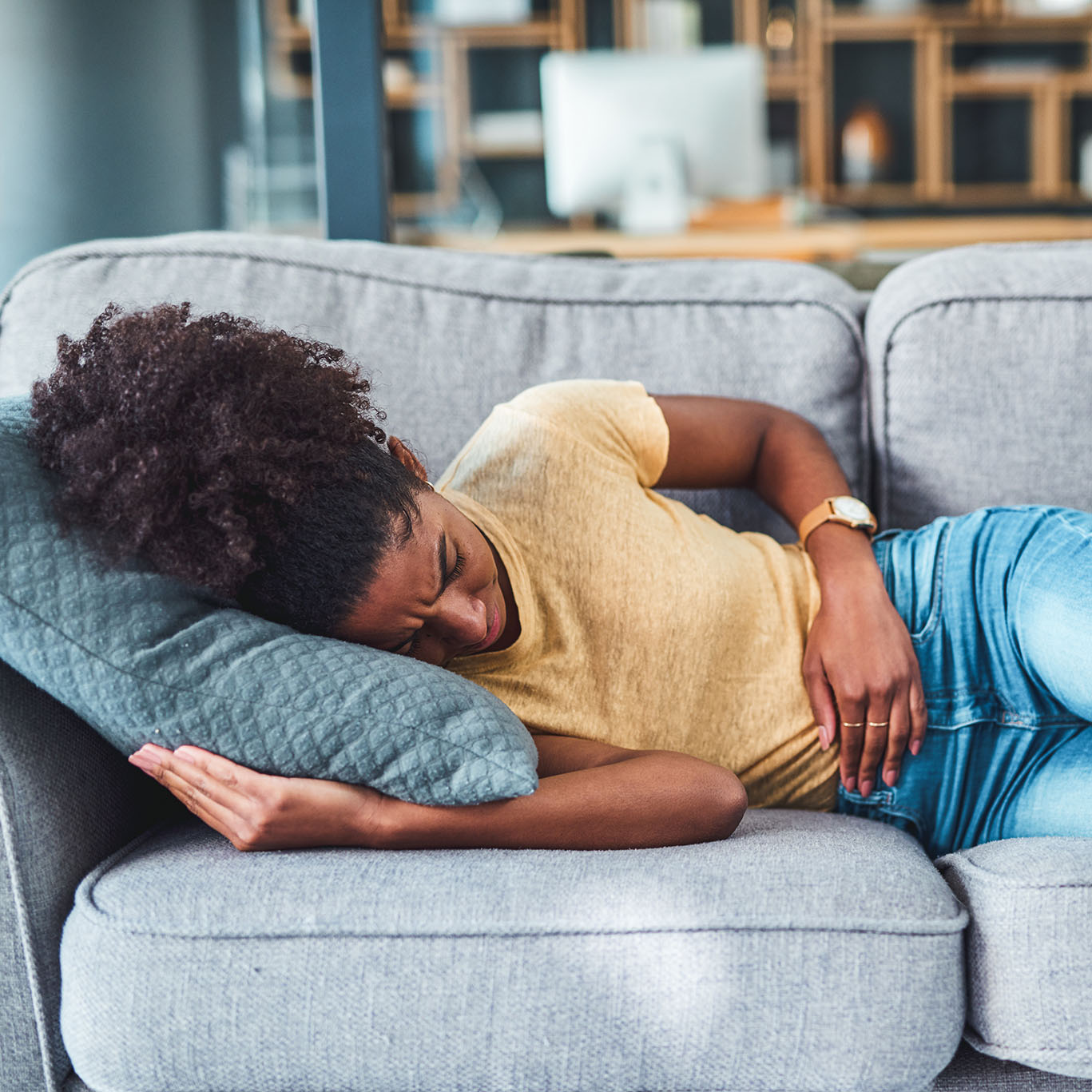 woman of color lying on couch with pelvic and abdominal pain